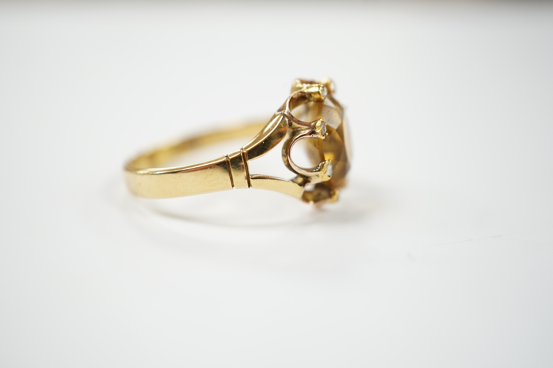 An 18ct and single stone oval cut citrine set dress ring, with eight stone diamond chip set border, size V